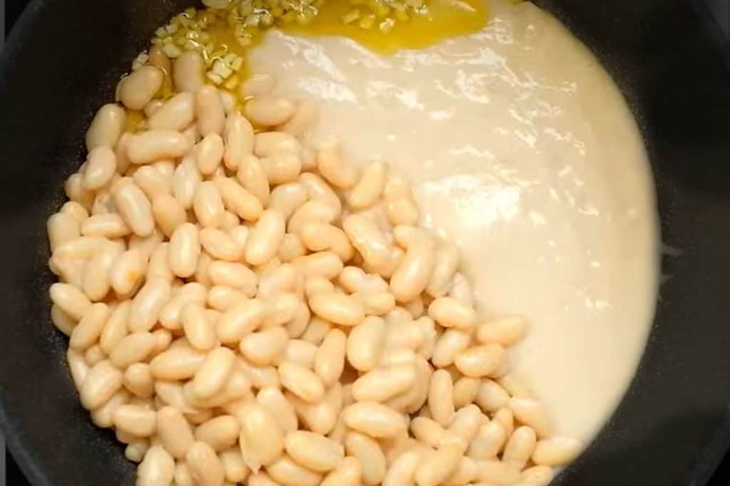 beans and pureed beans added to the pan with the garlic