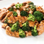 A close up of a white dish with the Chinese Chicken & Broccoli covered in a deep golden sauce.