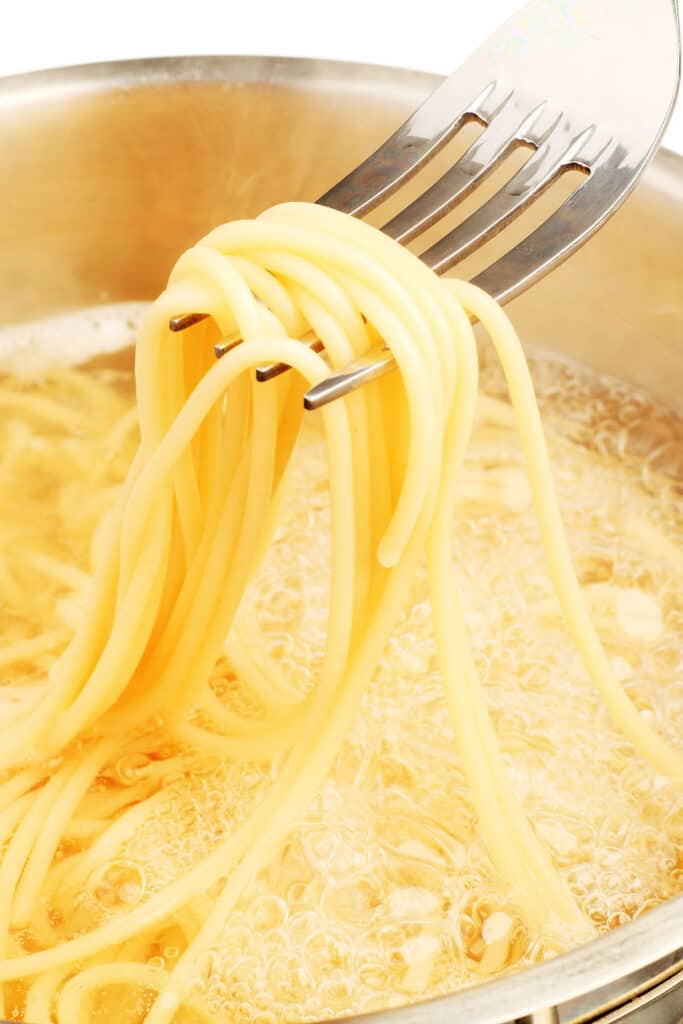a pot of spaghetti cookng in water with a fork taking some out
