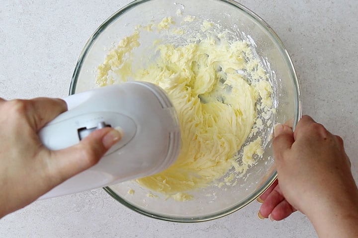 The buttercream being mixed with an electric mixer