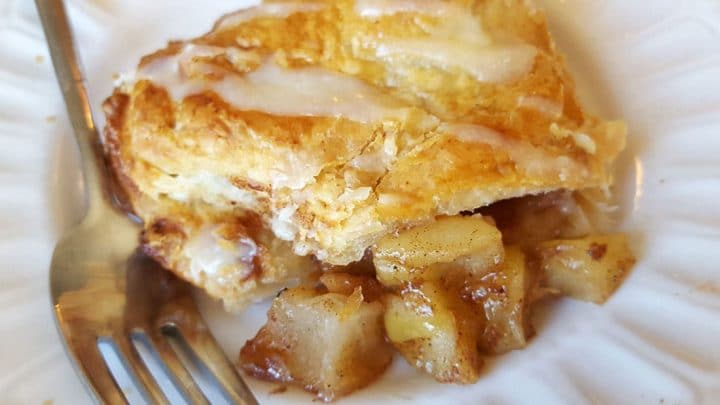 a apple turnover that's broken open with the filling falling onto the plate.