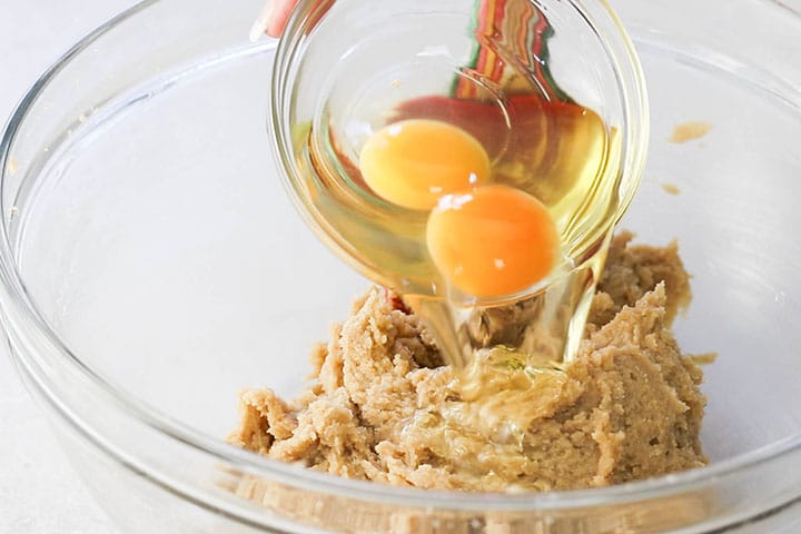 The eggs being added to the bowl with the butter mixture