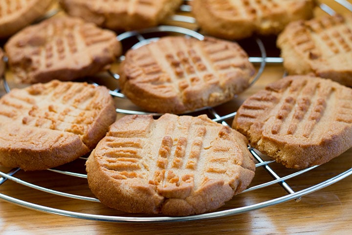 A cooling rack filled with fresh baked Classic Peanut Butter Cookies with golden edges and crisscross pattern