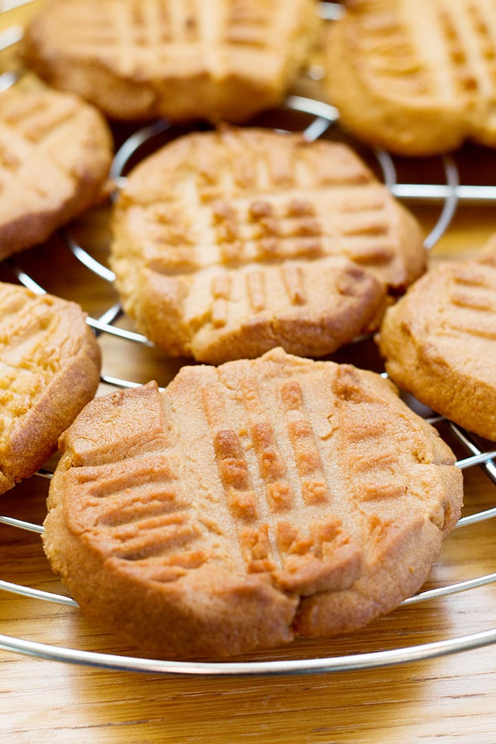 A cooling rack filled with fresh baked Classic Peanut Butter Cookies with golden edges and crisscross pattern