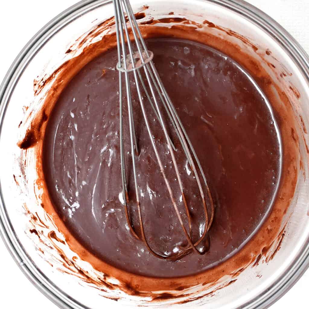 The chocolate melted into the cream in a glass bowl with a whisk.