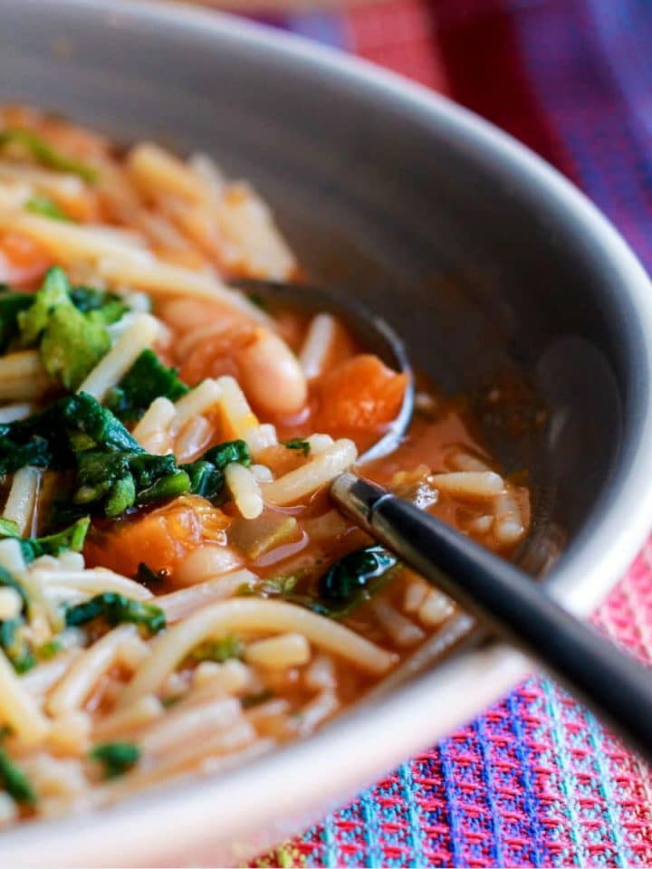 A long close up of bowl Ribollita Italian Soup with a spoon next to it.