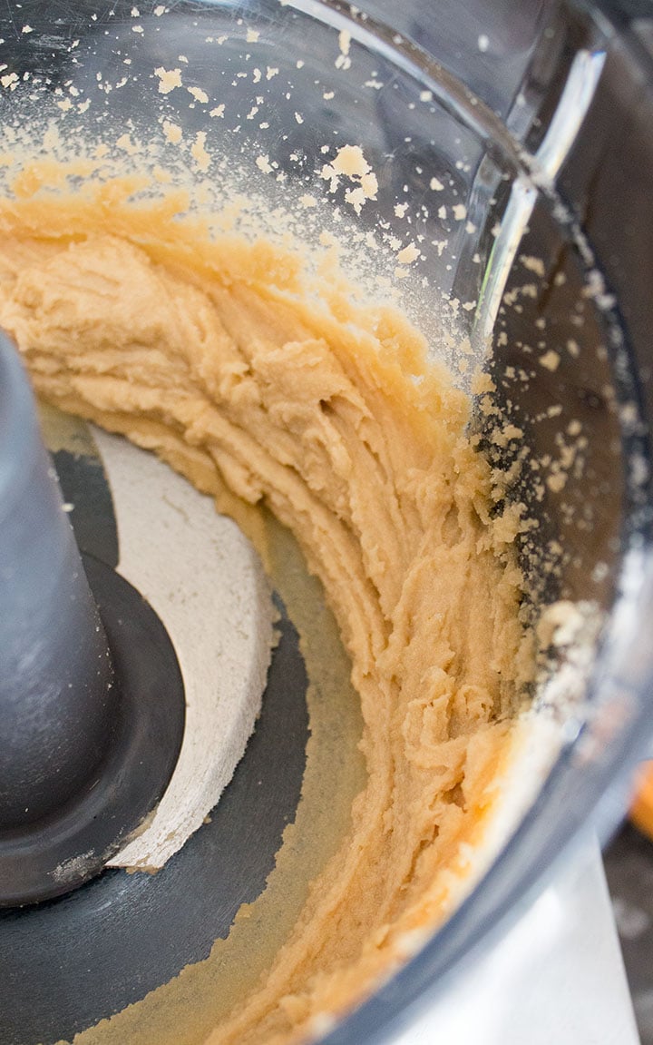 A close up of a food processor bowl with fluffy butter and sugar creamed together