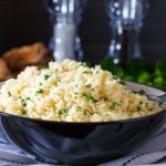 A bowl of rice Pilaf in a dish with salt and pepper mills in the background