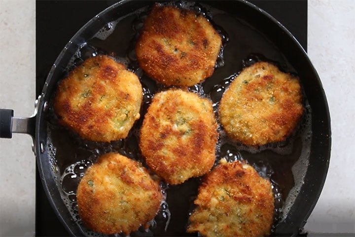 crab cakes frying in a pan