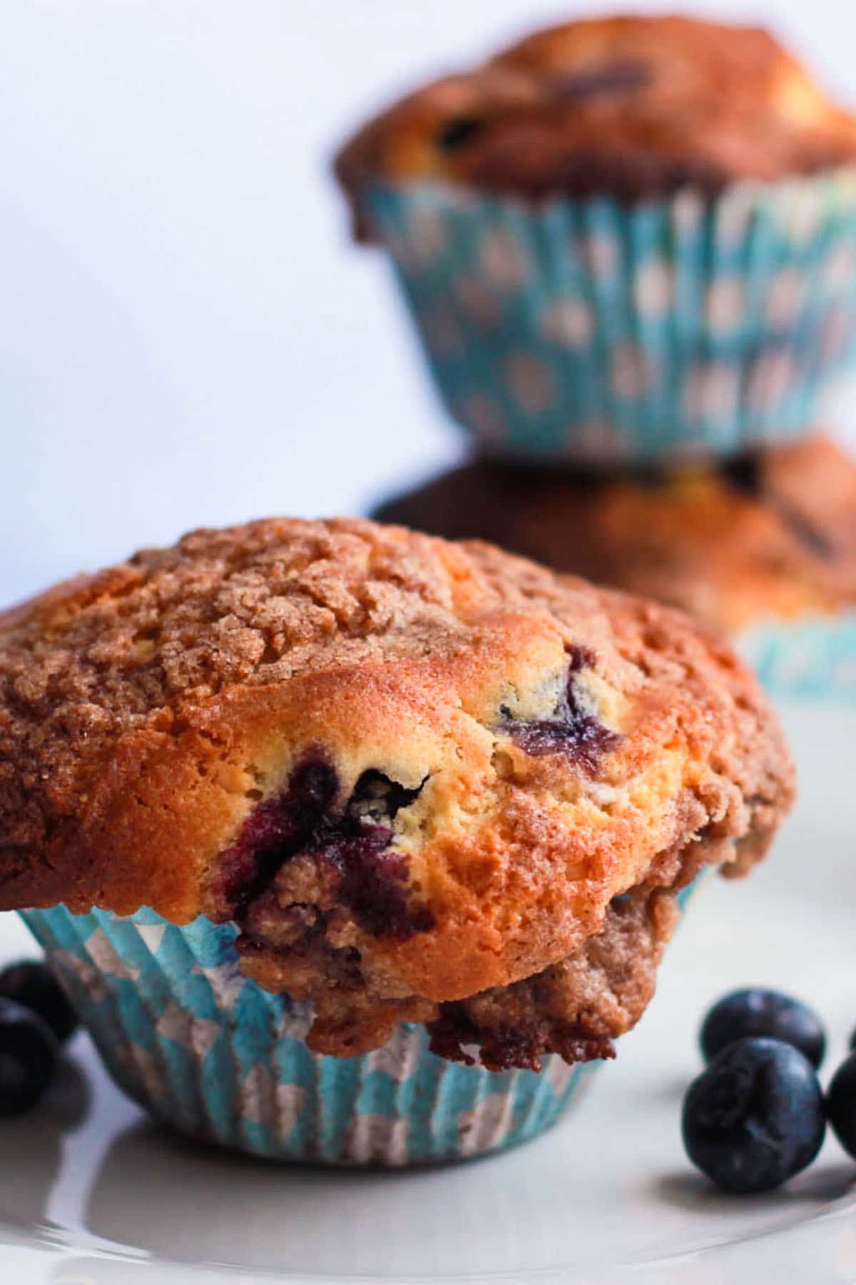 A Blueberry Crumb Cake Muffin on a plate with some fresh blueberries