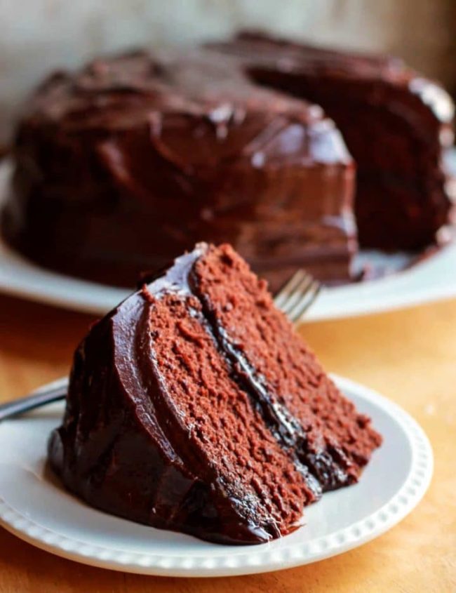 A slice of devils food cake with the cake in the background