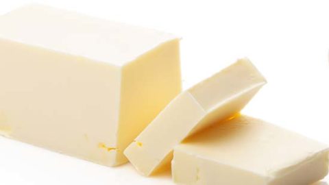 A close up of a stick of butter with some cut into cubes