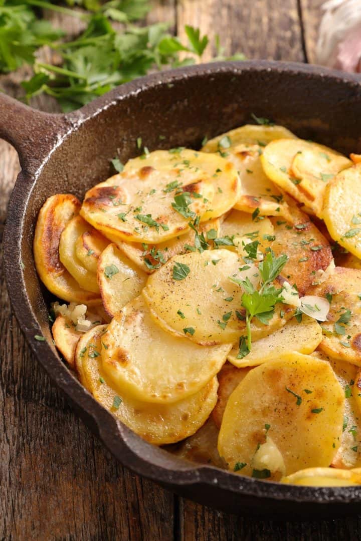 Crispy Garlic Roasted Potatoes in the pan with parsley scattered over it