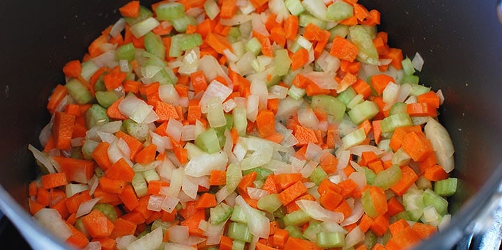 A pot with celery, carrots, and onions sauteing together.