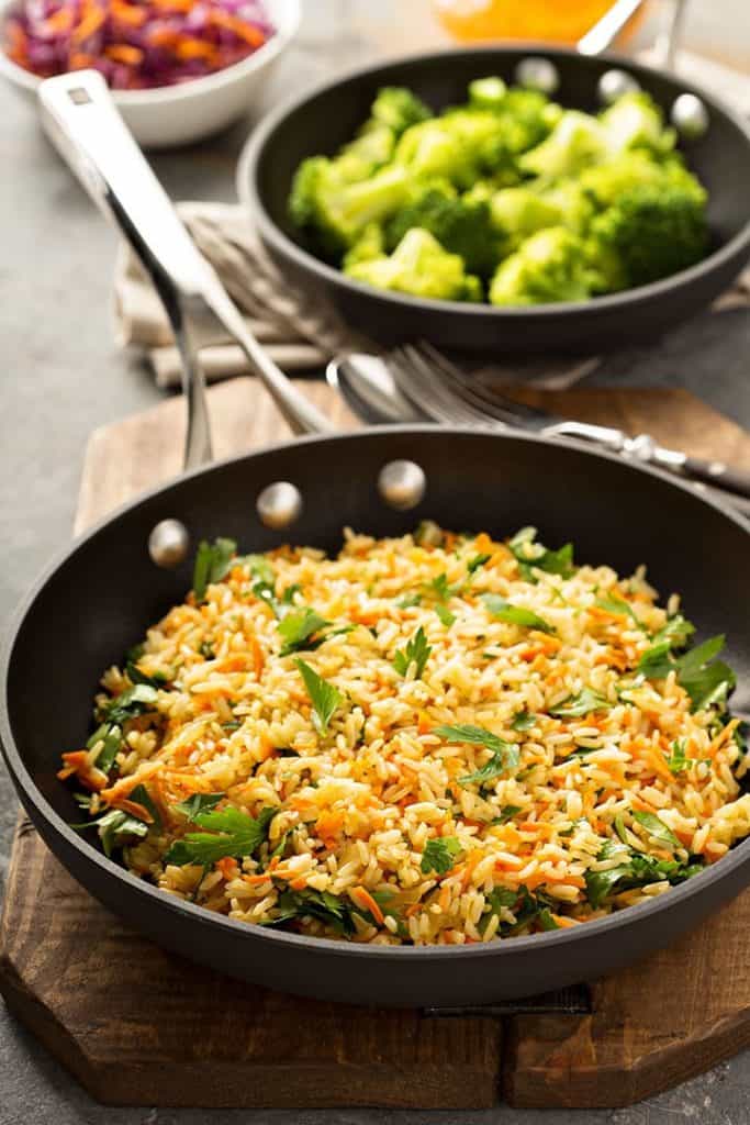 Vegetarian Rice Pilaf in a pan with dishes of vegetables in the background