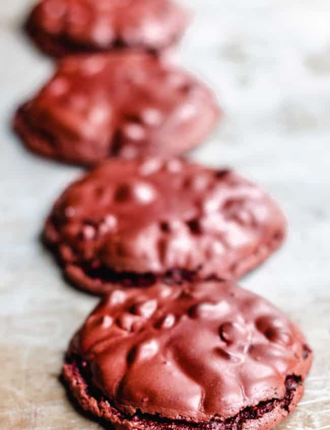 Four red velvet cookies lines up on a tray
