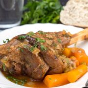 Slow cooked lamb shanks served with carrots on a plate