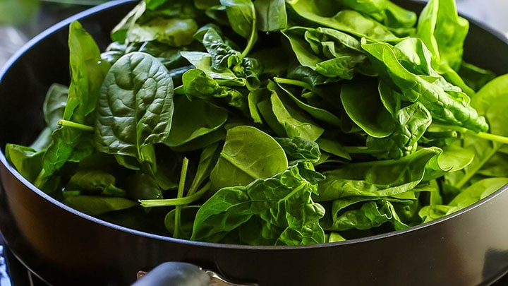 Spinach piled high in a pan.