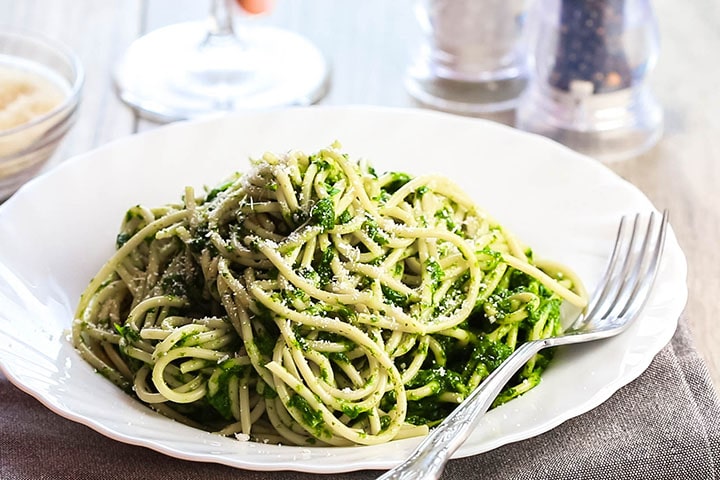 A bowl of Spaghetti with Spinach Sauce with a fork next to it on the plate