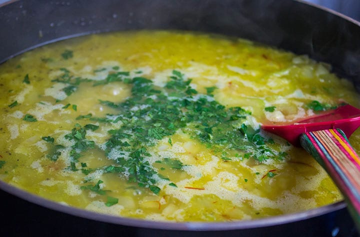 The stock and saffron added to the pan with the parsley.