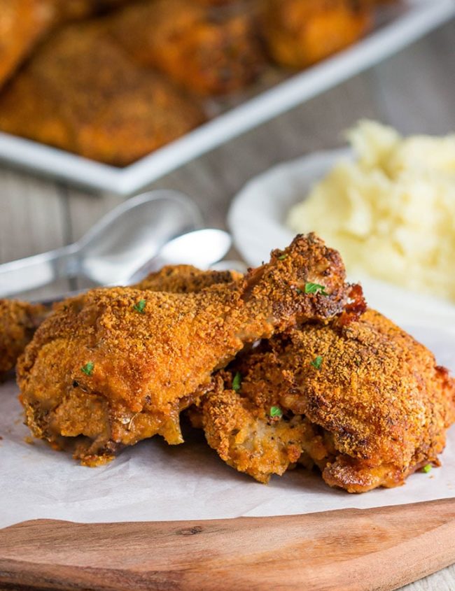 Three pieces of Easy Oven Fried Chicken speckled with parsley.