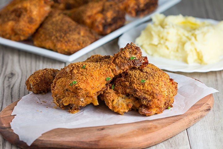 Three pieces of Easy Oven Fried Chicken speckled with parsley 