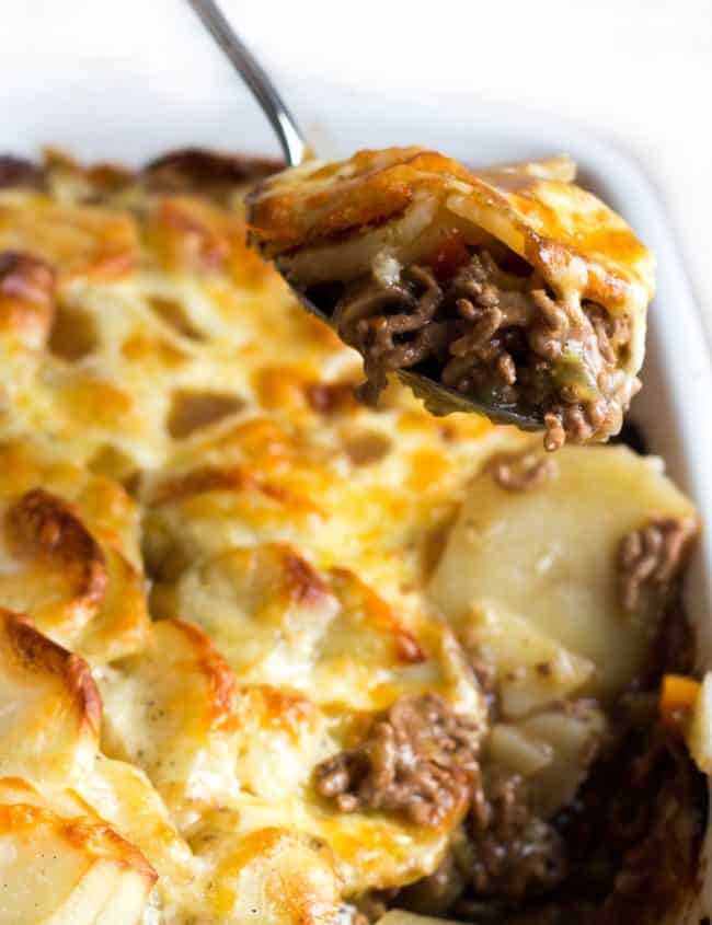 a spoon serving cottage pie stopped with cheesy potatoes