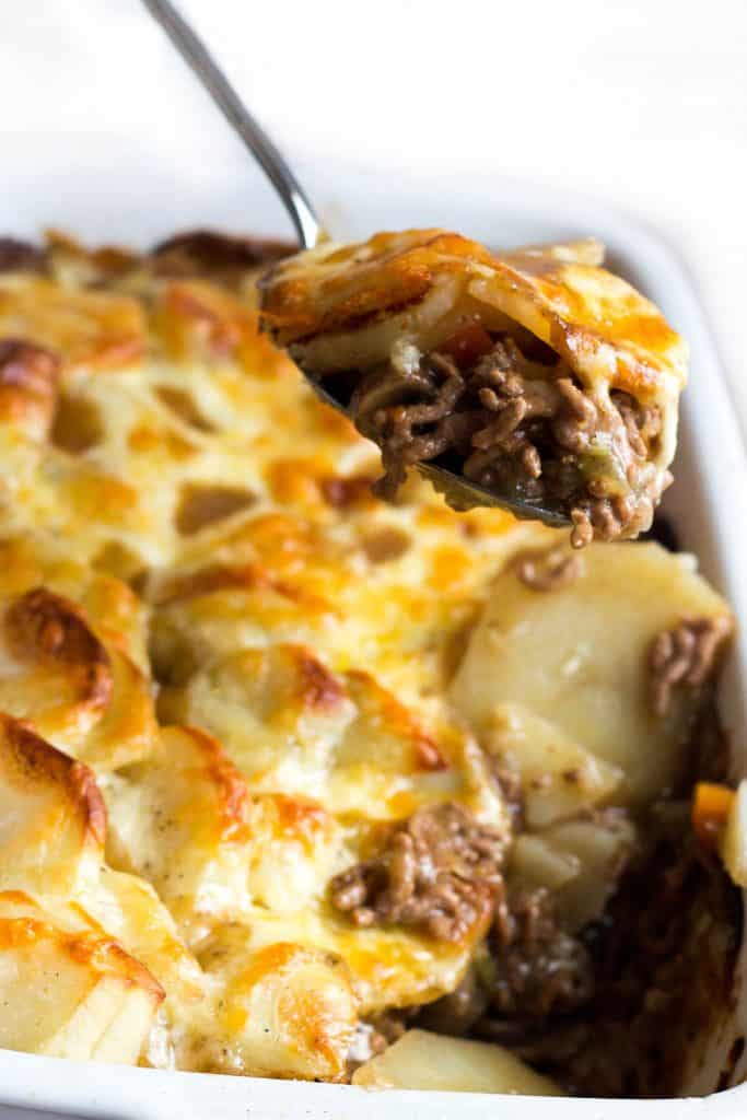 a spoon serving cottage pie stopped with cheesy potatoes