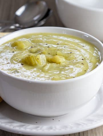 A bowl of Creamy Celery Soup with crackers on the side of the bowl