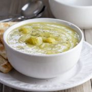A bowl of Creamy Celery Soup with crackers on the side of the bowl