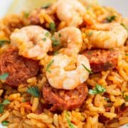 a plate of bright yellow saffron rice topped with chorizo and shrimp