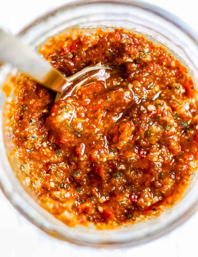 a jar of red pesto with a spoon in it