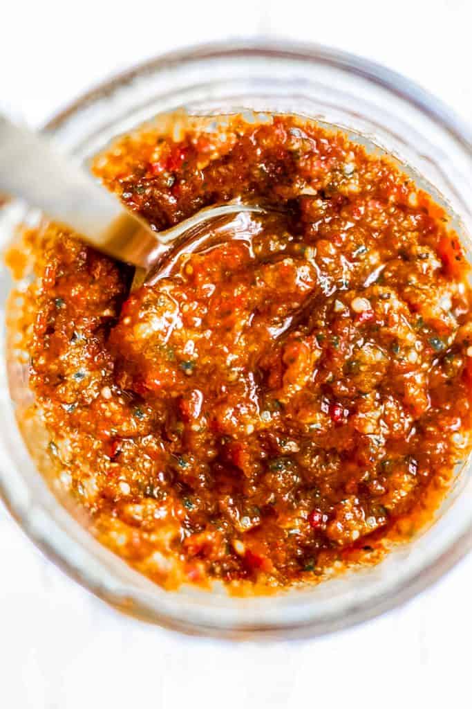 a jar of red pesto with a spoon in it