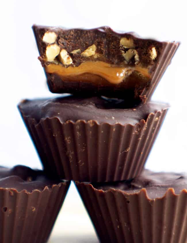 4 homemade snickers candies with one cut open to see the caramel and peanuts inside