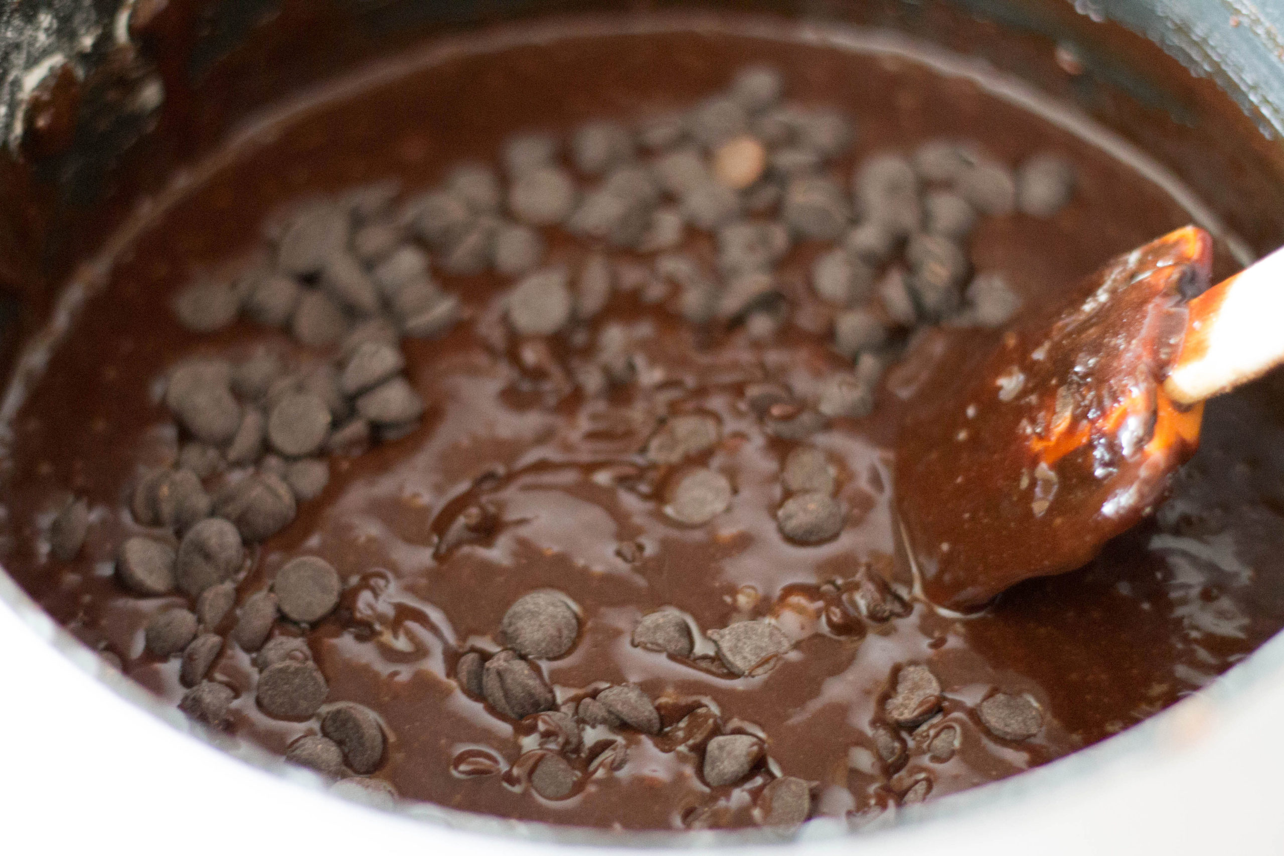 chocolate chips melting in a pan being stirred with a spoon