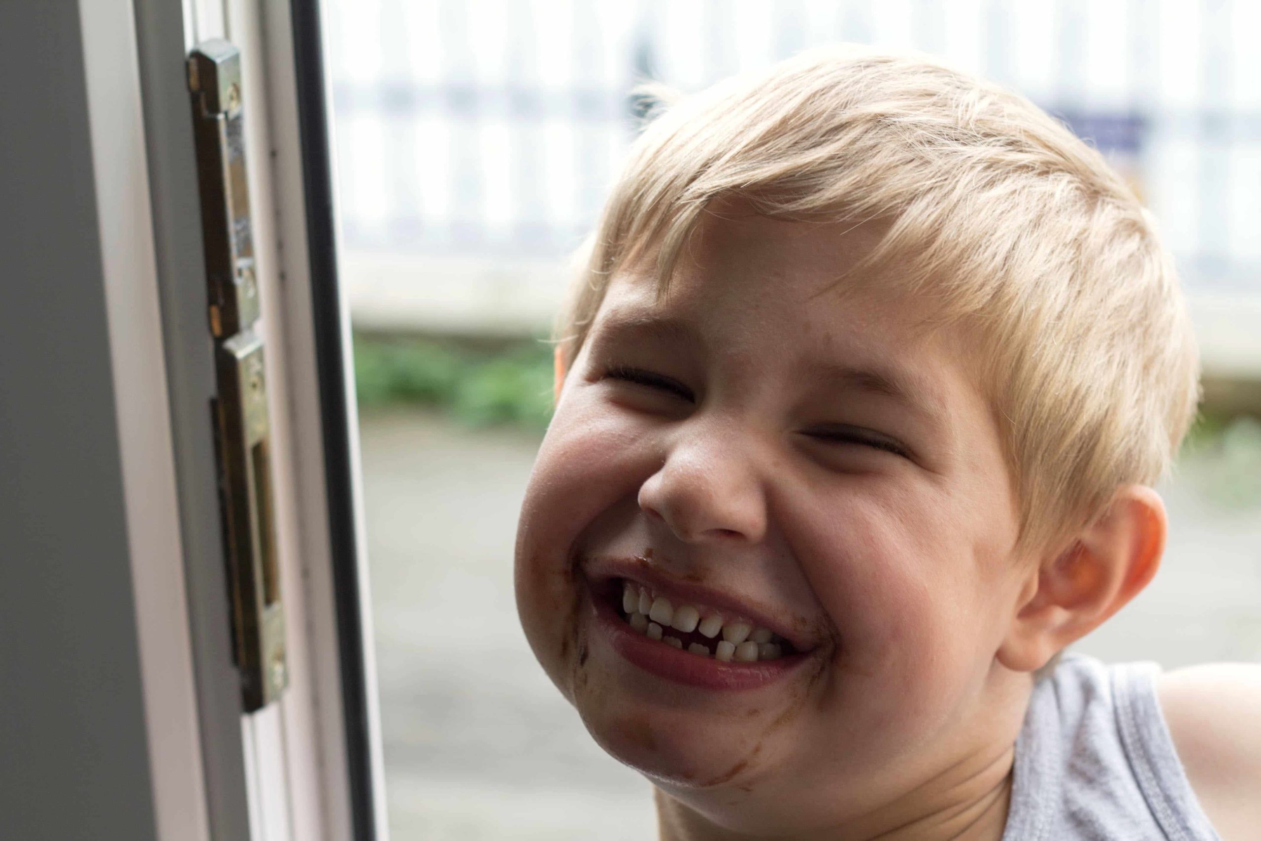 a boy with chocolate around his mouth, smiling