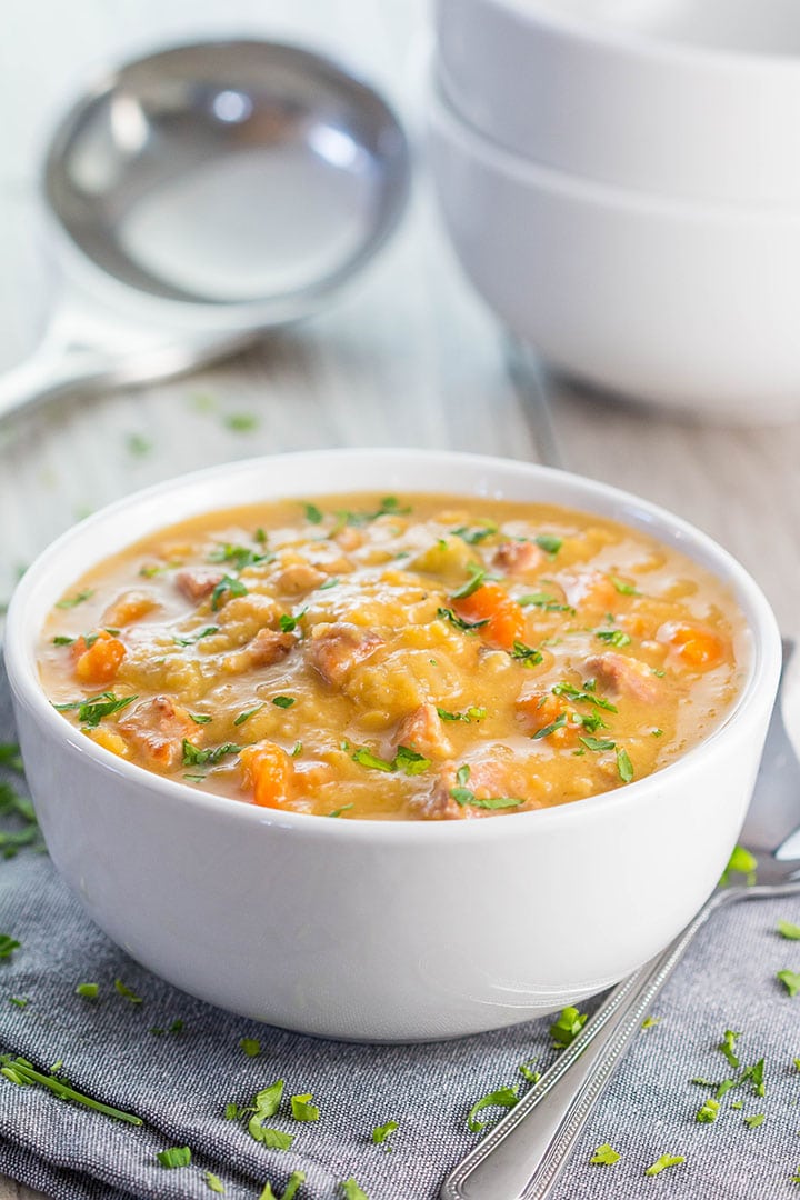 Yellow Split Pea and Bacon Soup in a white bowl with a ladle in the background