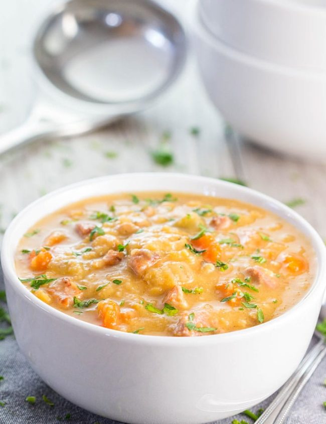 Yellow Split Pea and Bacon Soup in a white bowl with a ladle in the background