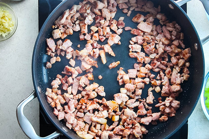 Chopped bacon cooking in a pan