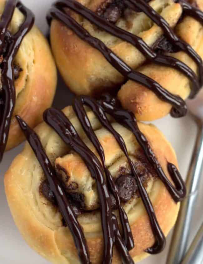 close up of chocolate swirl buns drizzled in chocolate