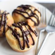 A close up of a plate of chocolate swirl buns on a plate and two forks