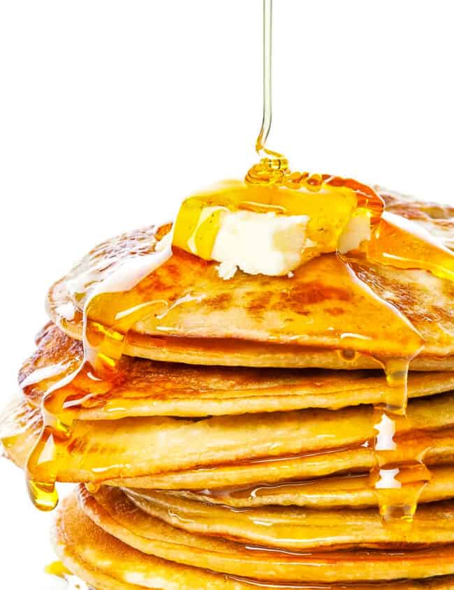 A pile of johnny cakes with butter and syrup.