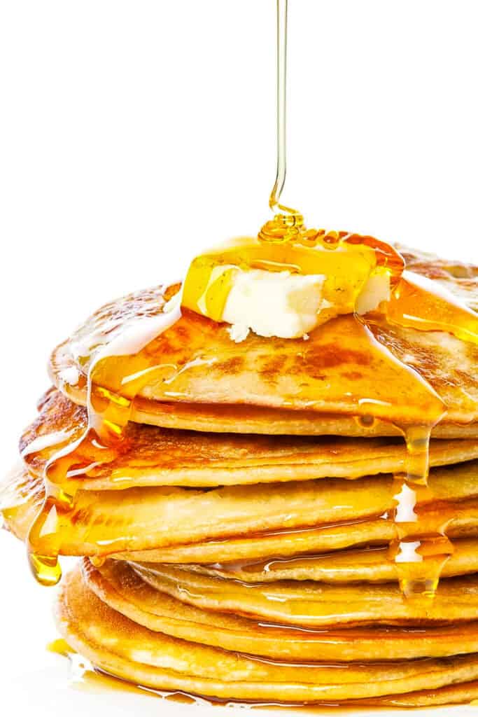 a pile of johnny cakes with butter and syrup