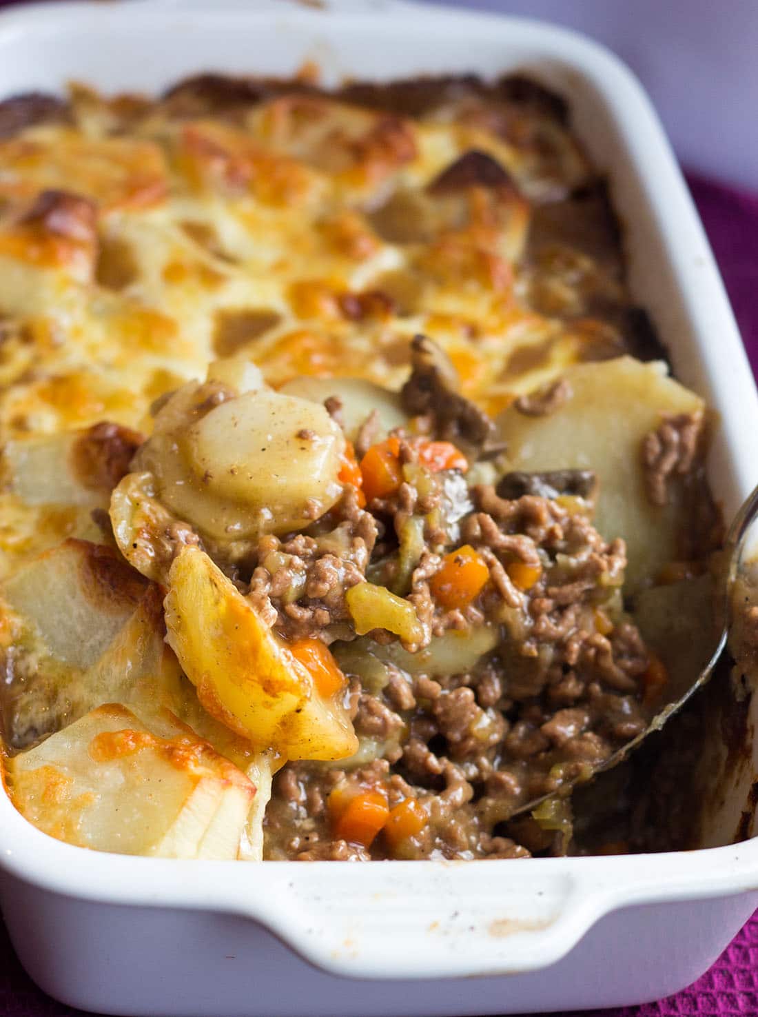 A serving dish with cottage pie with a spoonful removed