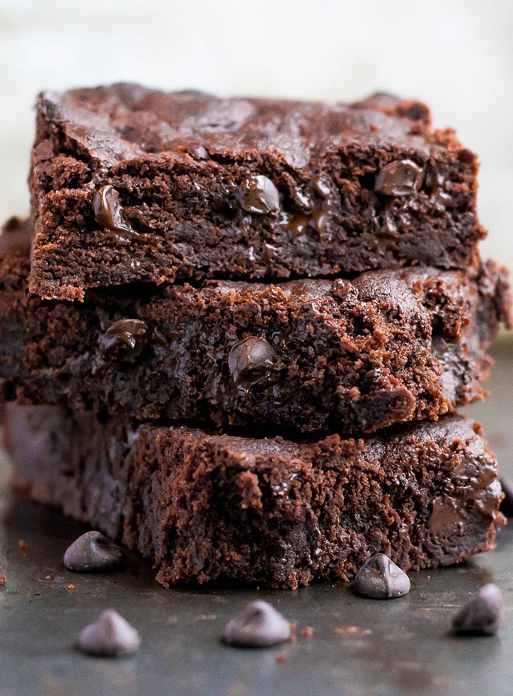 A stack of three double chocolate chip bars with melted chocolate chip cookies dotted throughout 