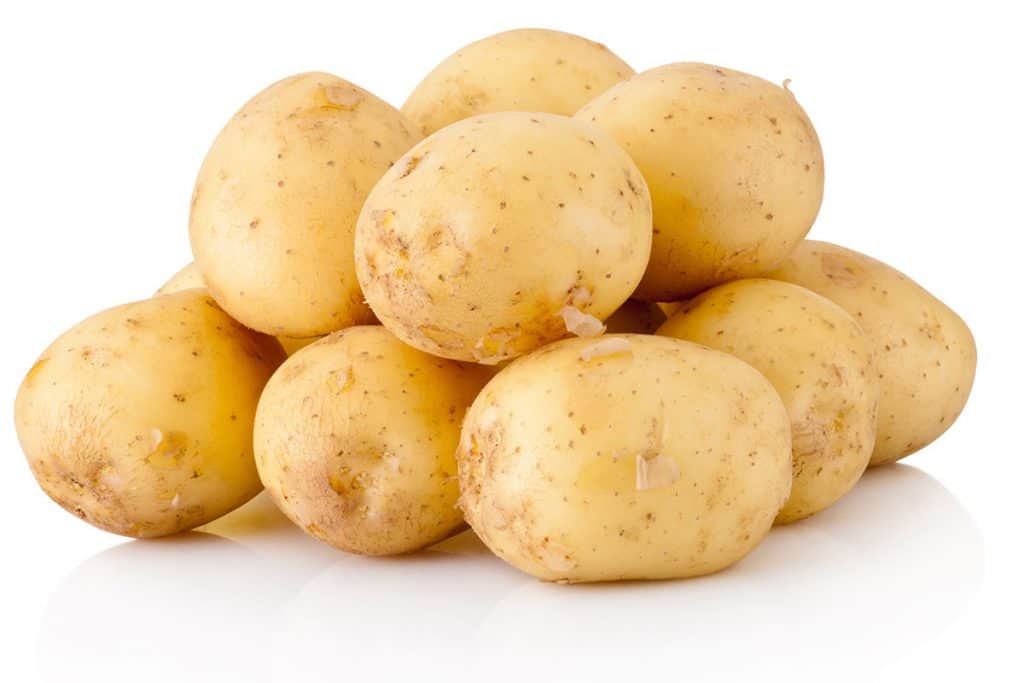 A pile of raw, unpeeled potatoes with a white background