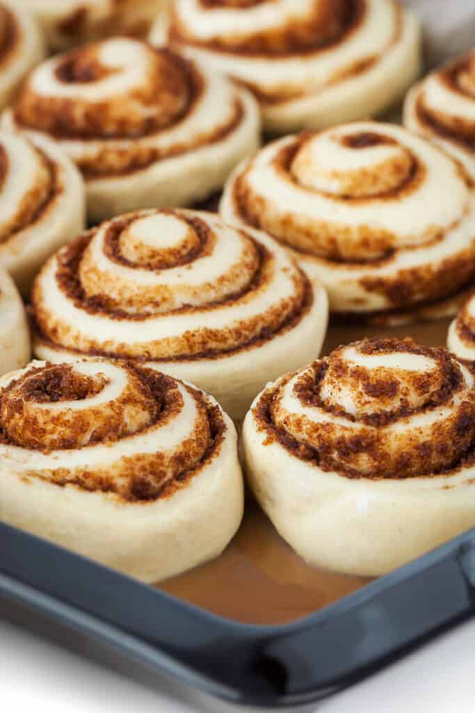 the raised buns in the pan of sauce ready to bake.