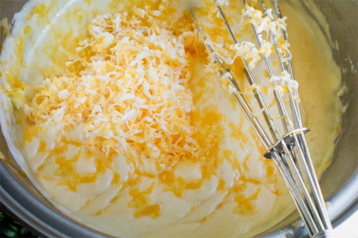 A pot with the cheese being mixed into the milk mixture.