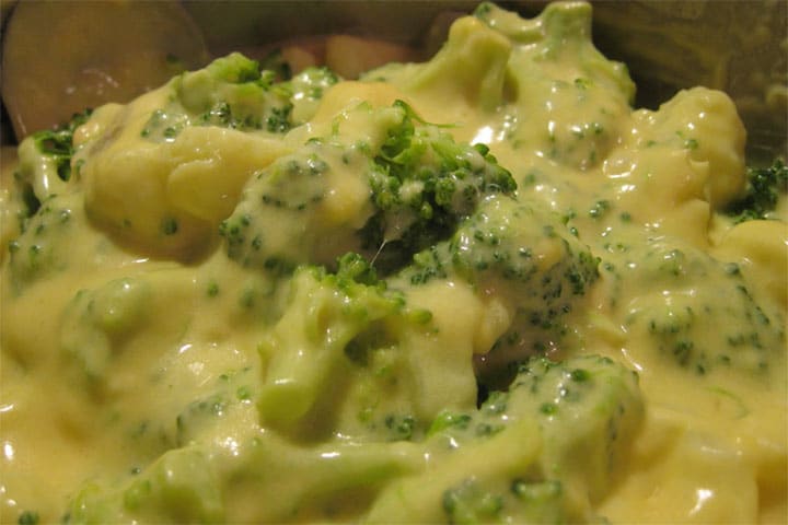 a close up of the broccoli and cauliflower coated in the thick cheese sauce