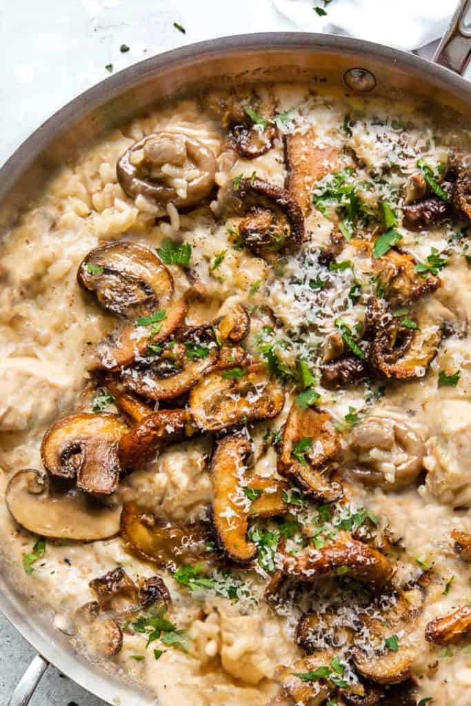 A close up of chicken and mushroom risotto sprinkled with chopped parsley and parmesan